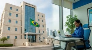 Funcionário administrativo trabalhando em escritório moderno na Embaixada do Brasil em Doha, com bandeira brasileira ao fundo, representando o processo seletivo para vaga de Auxiliar Administrativo em 2025.